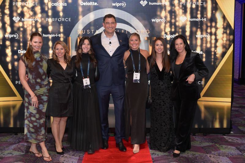 Guests on the IMPACT Awards red carpet with sponsor backdrop